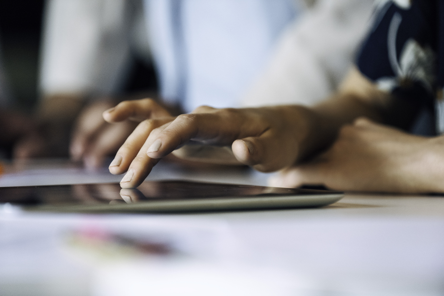 A close up shot of a man with a printed navy shirt touching his ipad that is laying down on the desk, Q3 2021, TAA NA US - Preparer