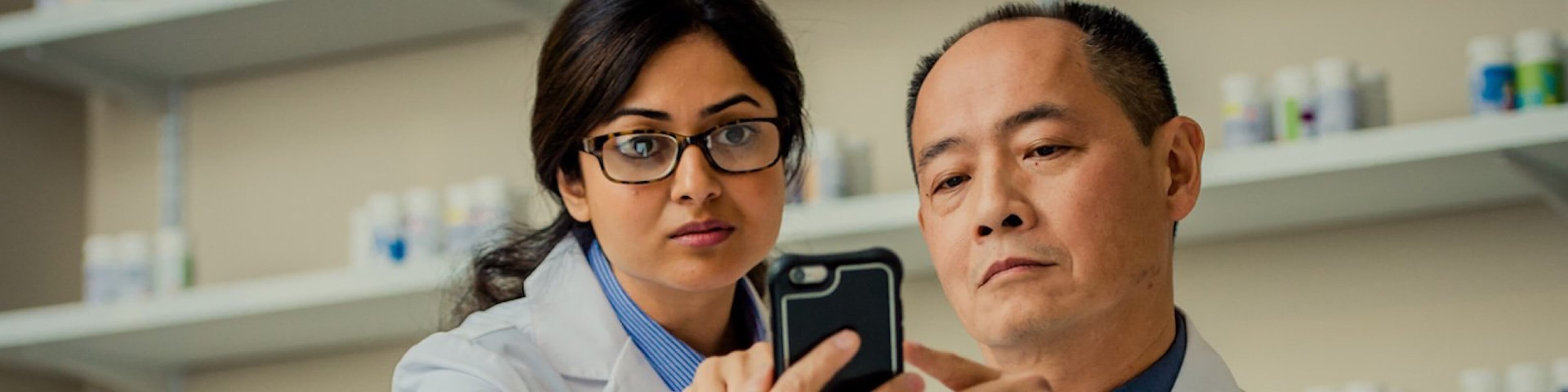 Pharmacists looking at data on a mobile device