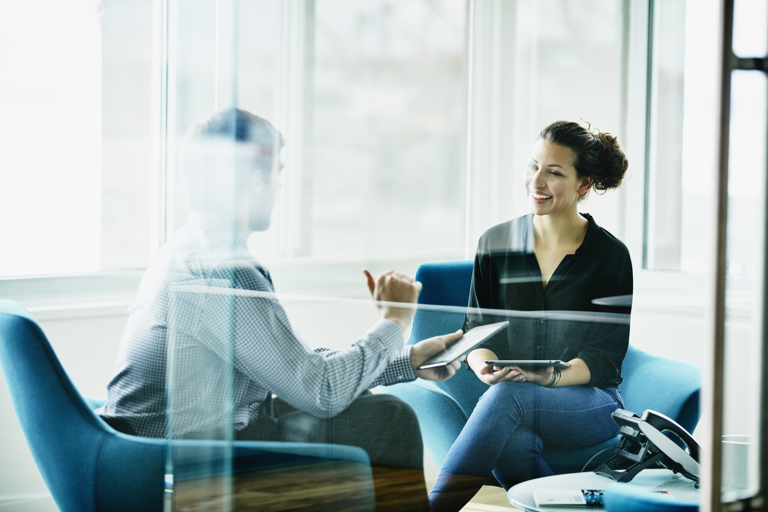 Businessman and businesswoman discussing project on digital tablets during meeting in office