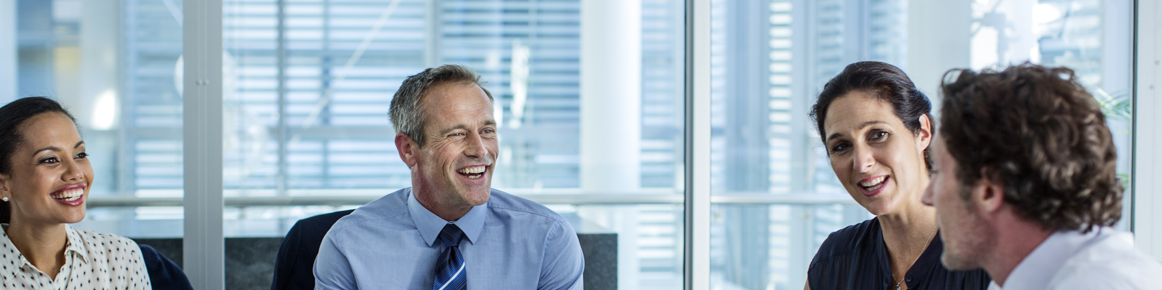 Happy business professionals discussing at conference table in office.