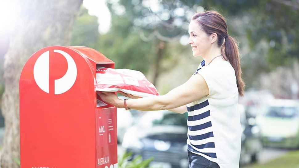 photo-woman-putting-satchel-in-red-street-posting-box