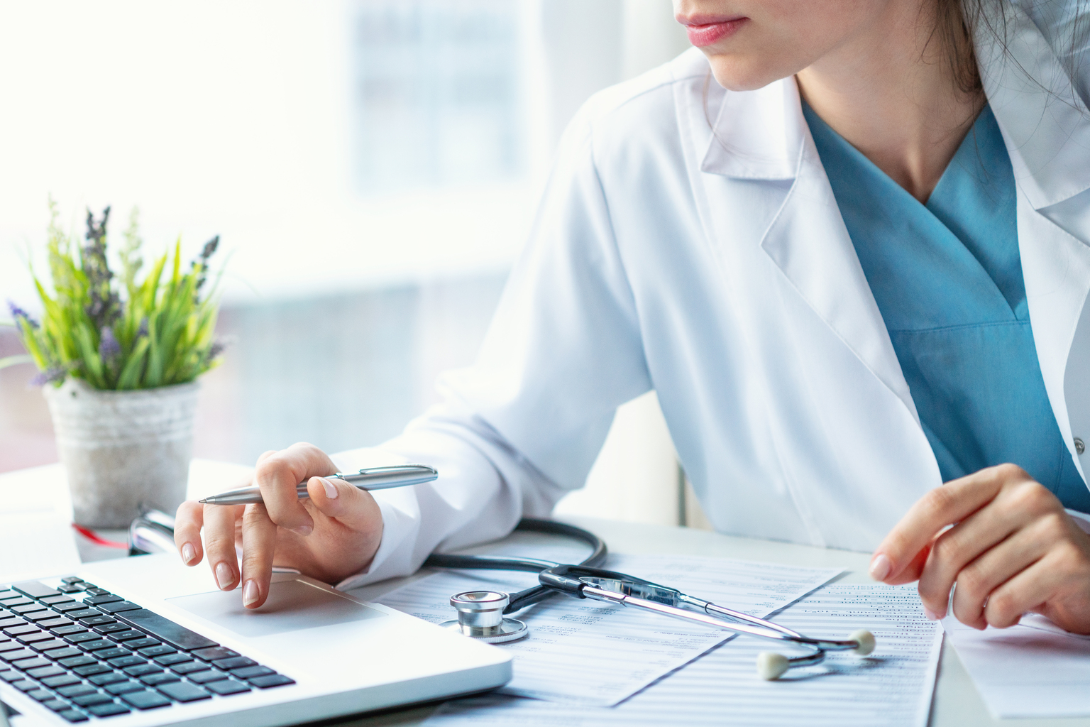 Female doctor working at laptop computer in doctor office