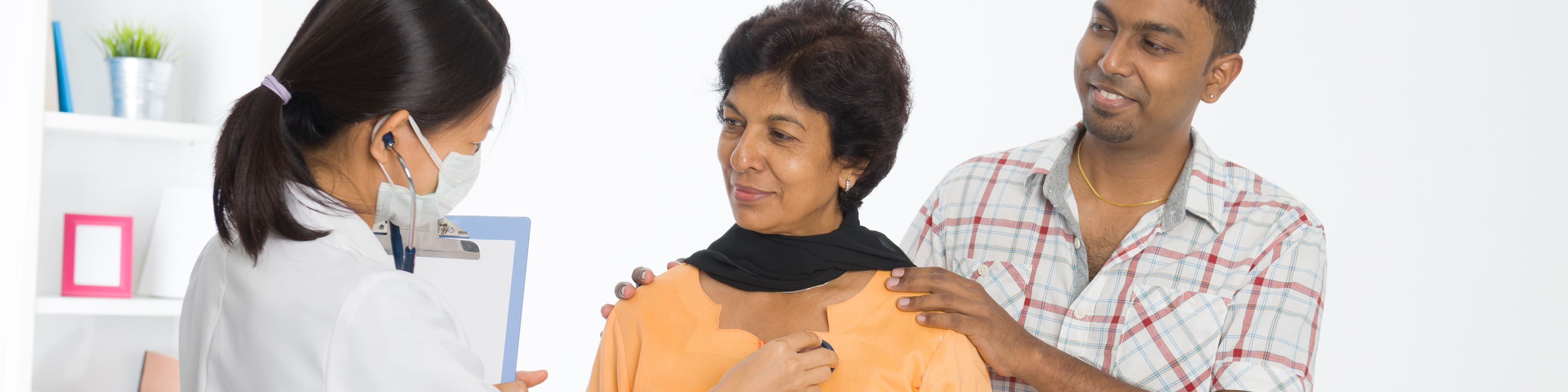 Doctor checking patient's upper chest with stethoscope while supportive family member is standing next to patient