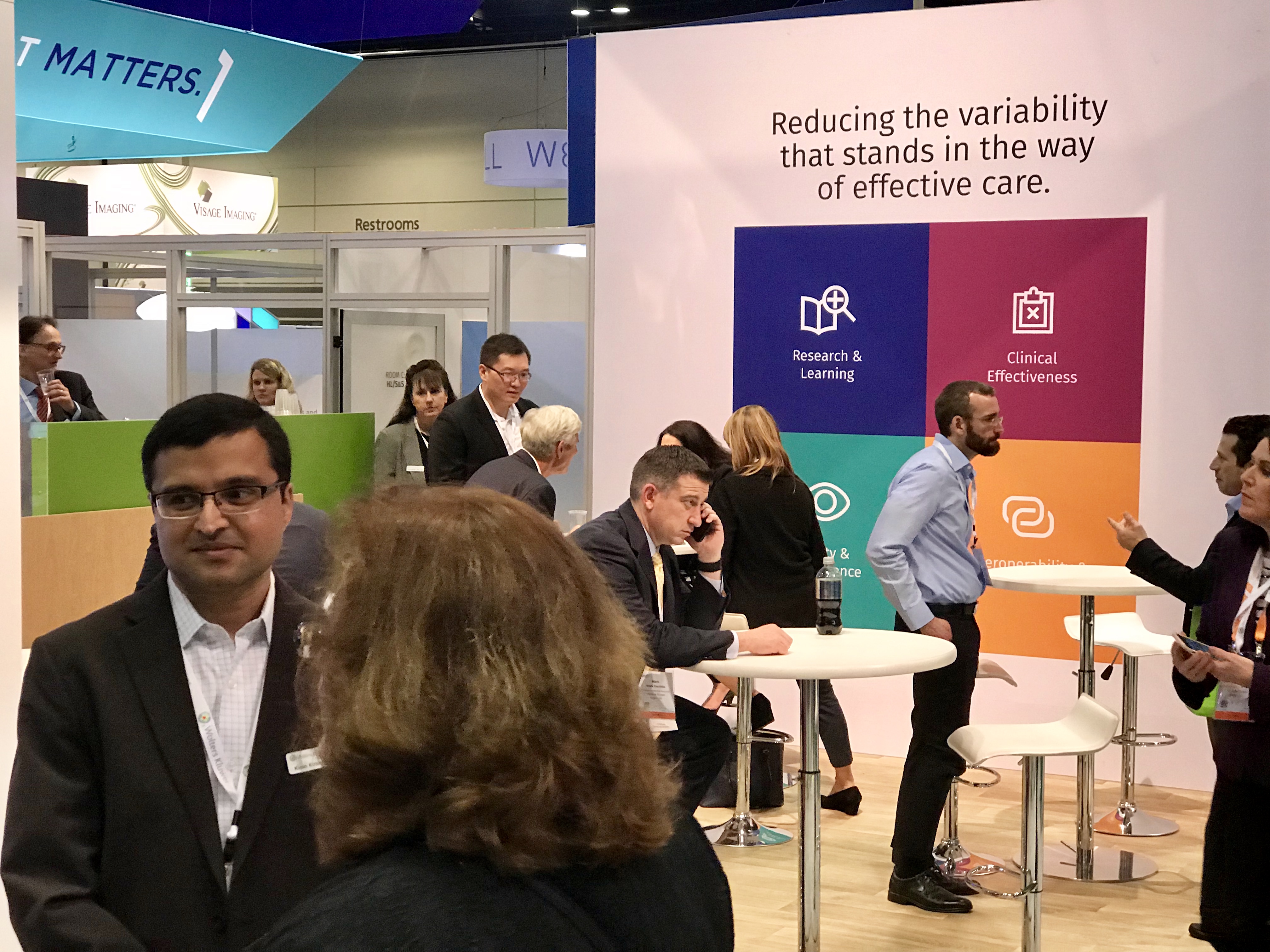 People gather and network at the Wolters Kluwer Health booth at HIMSS 2019 conference.