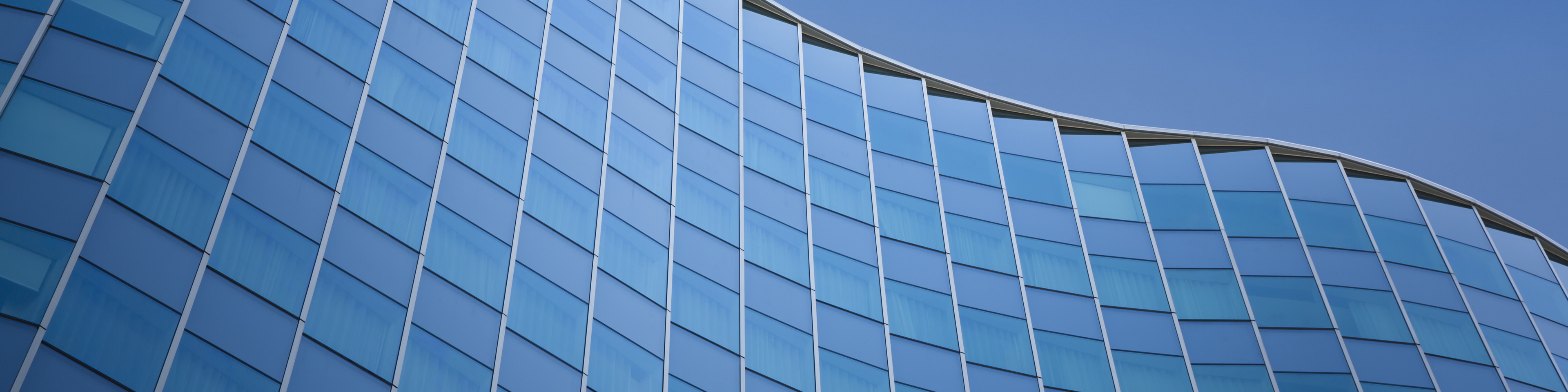 Close up of a modern architecture with blue sky background - glass building exterior