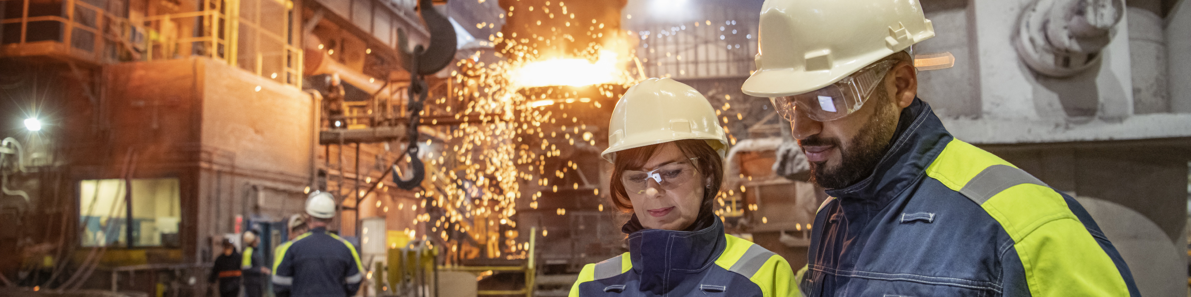 Man and woman coworkers looking at the tablet at industrial facility in steel industry