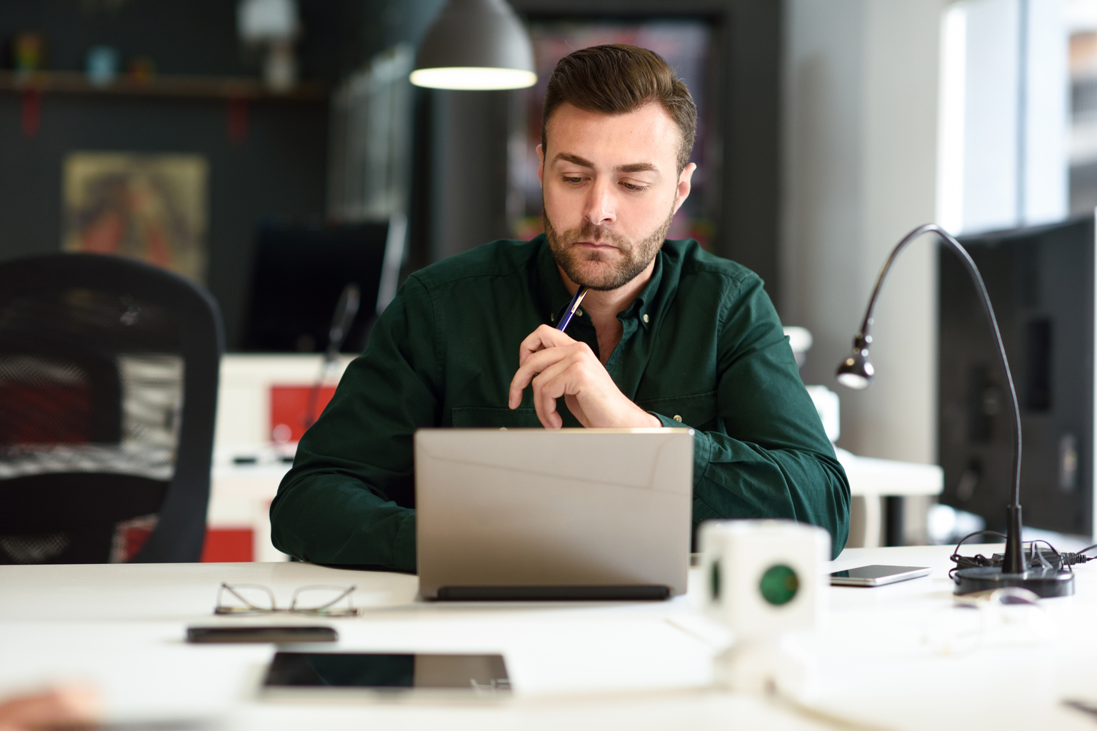 Young man studying with laptop computer on white desk