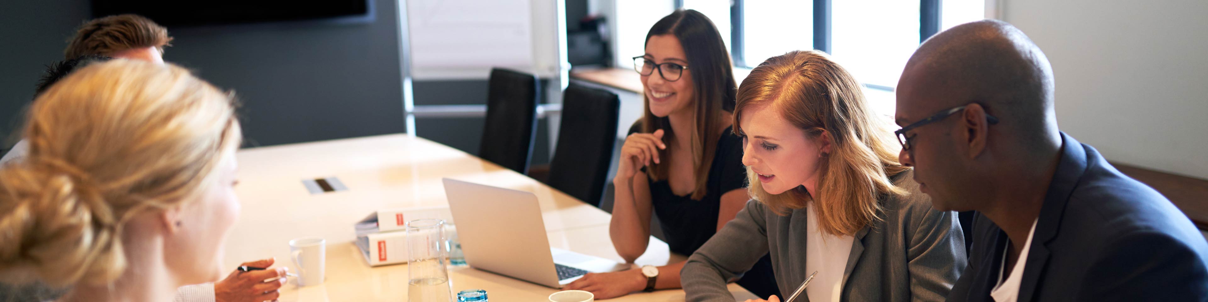 5 businesspeople sitting around a table having a meeting