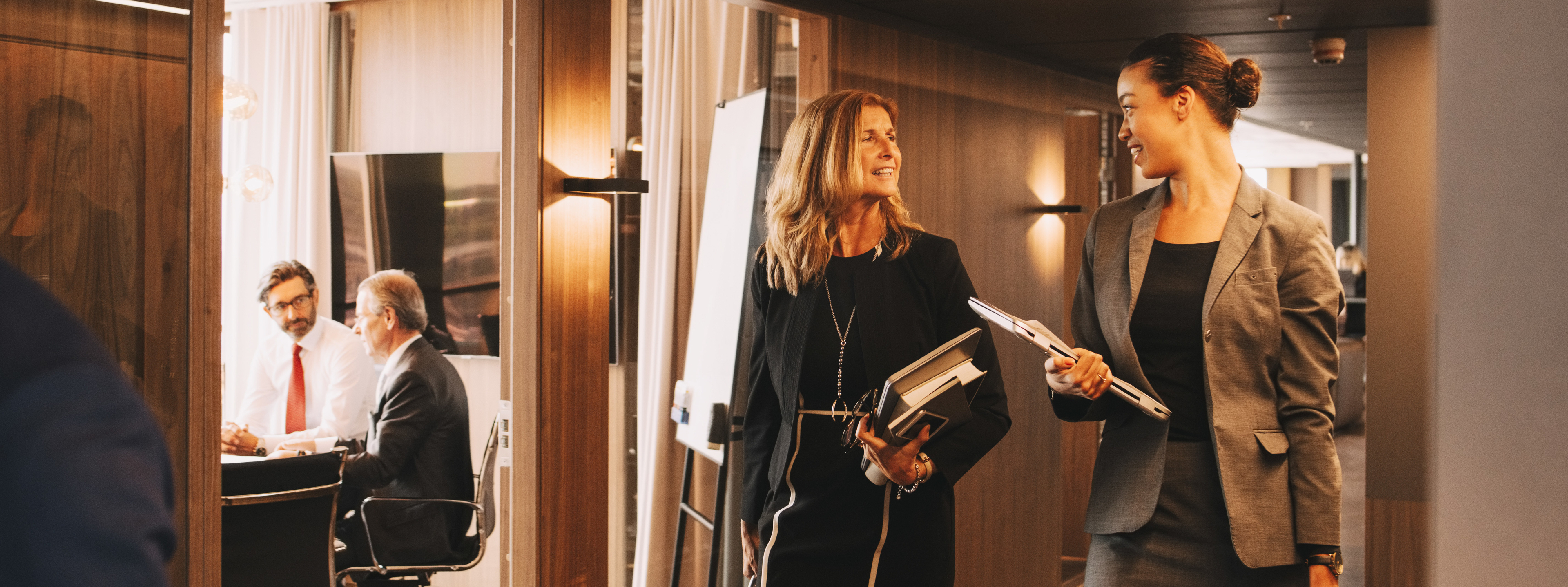 Female lawyers discussing while colleagues planning in background at law office 