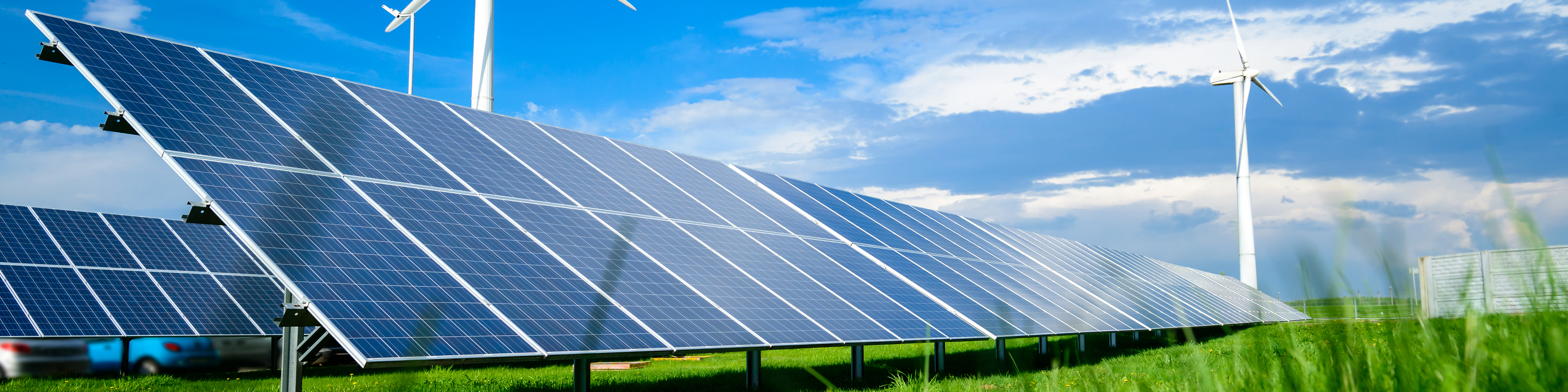 Solar energy panels and windmills against blue sky on summer day, background