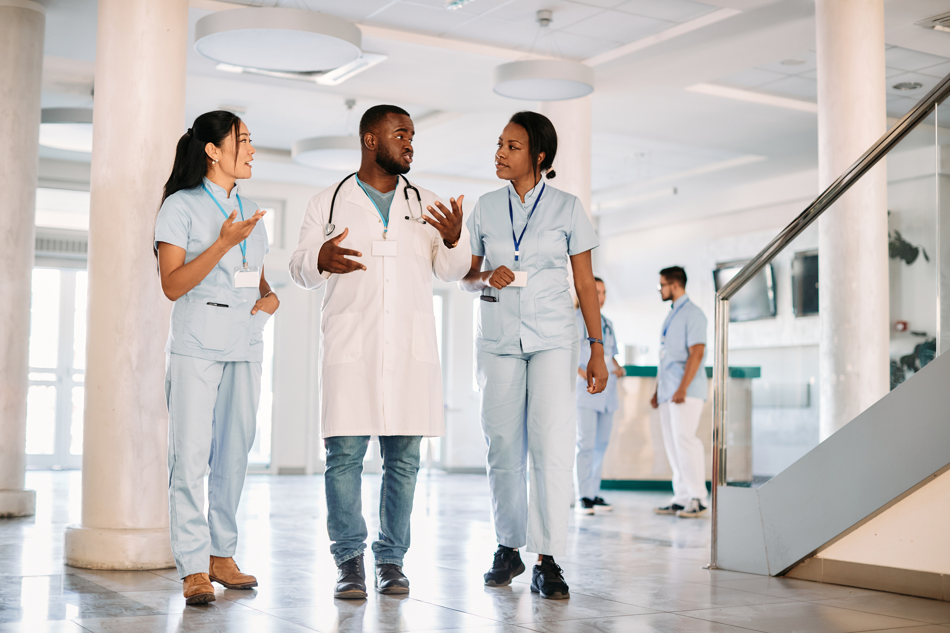 Group of young students talk while walking through medical university hallway.