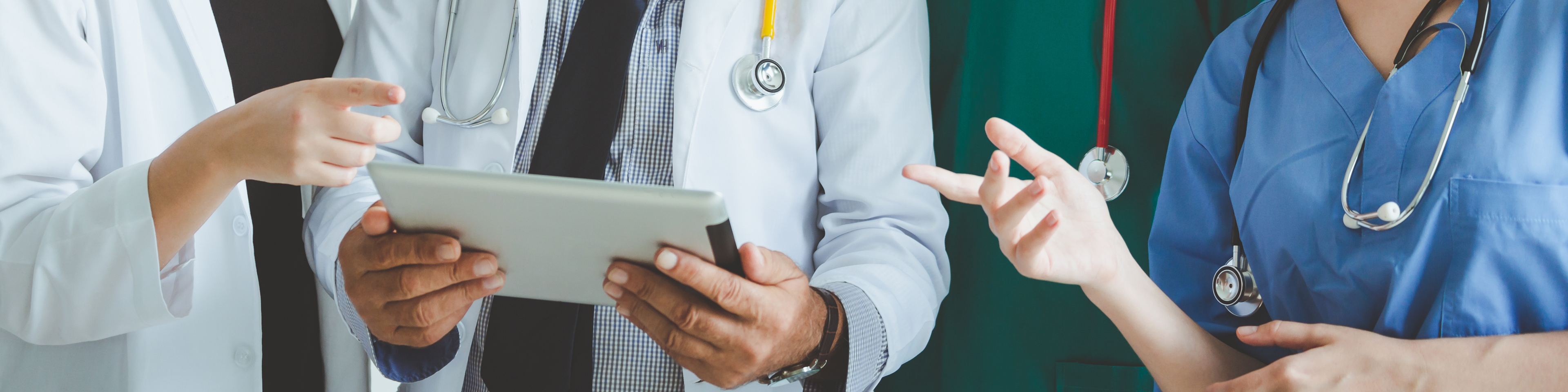 Group of healthcare workers conversing over a tablet