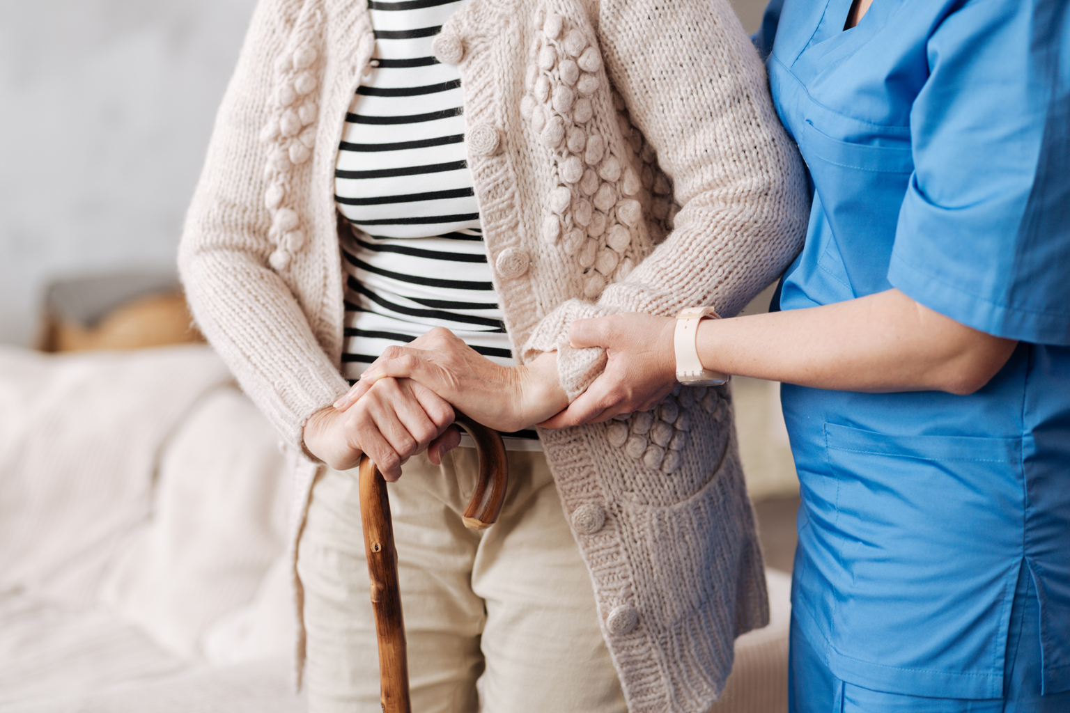 Gentle trained nurse helping cane-using mature patient