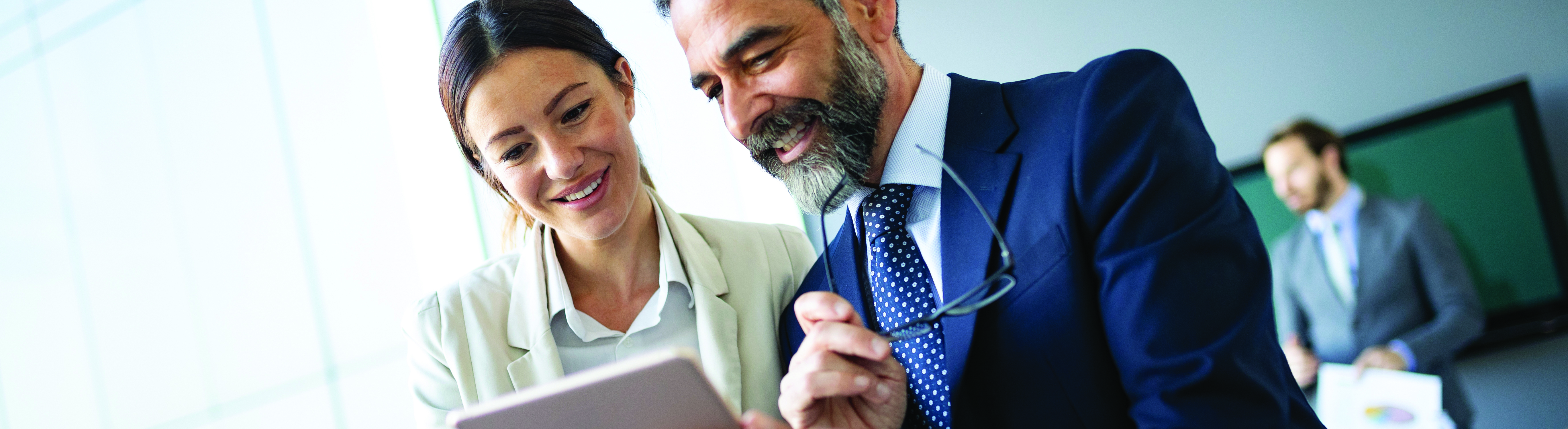 Happy business colleagues in a modern office using a tablet.