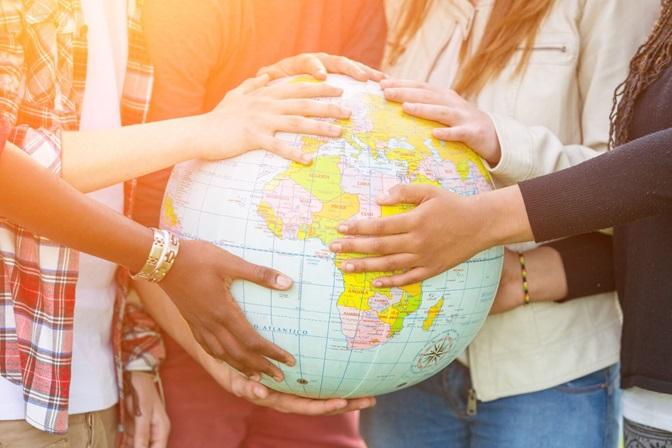 Diverse hands on globe of world