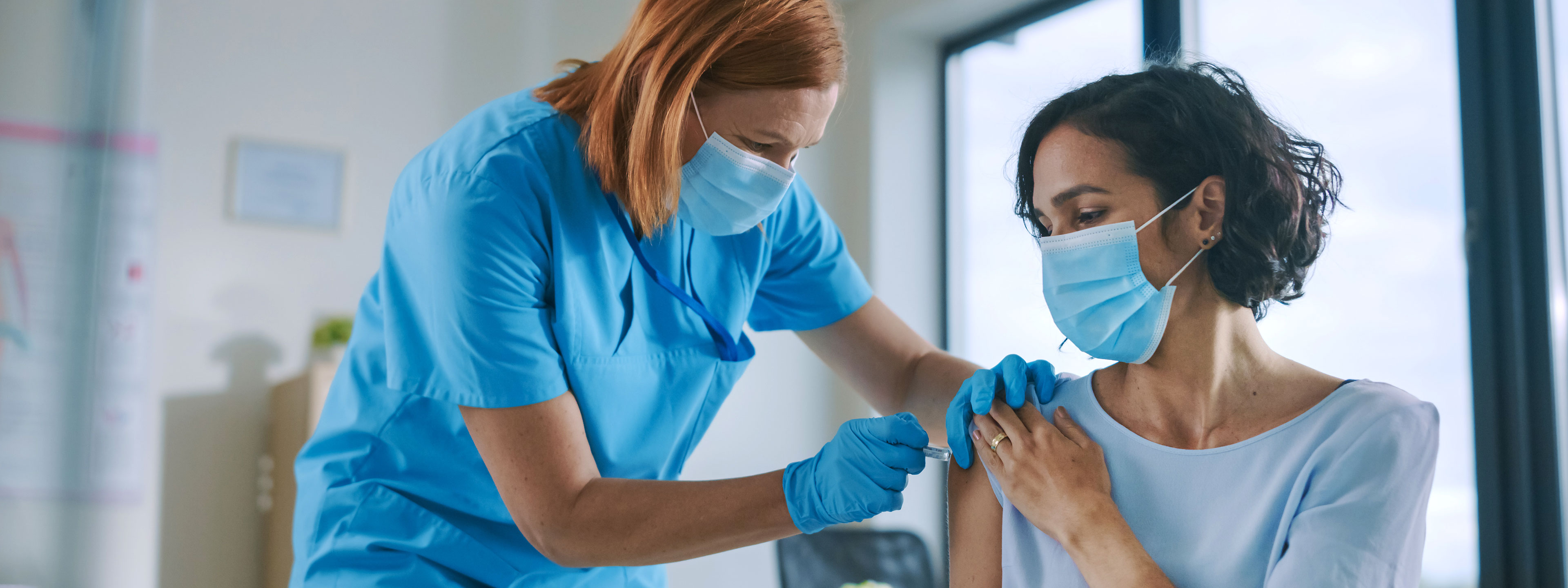 female doctor inserting vaccine into female patient