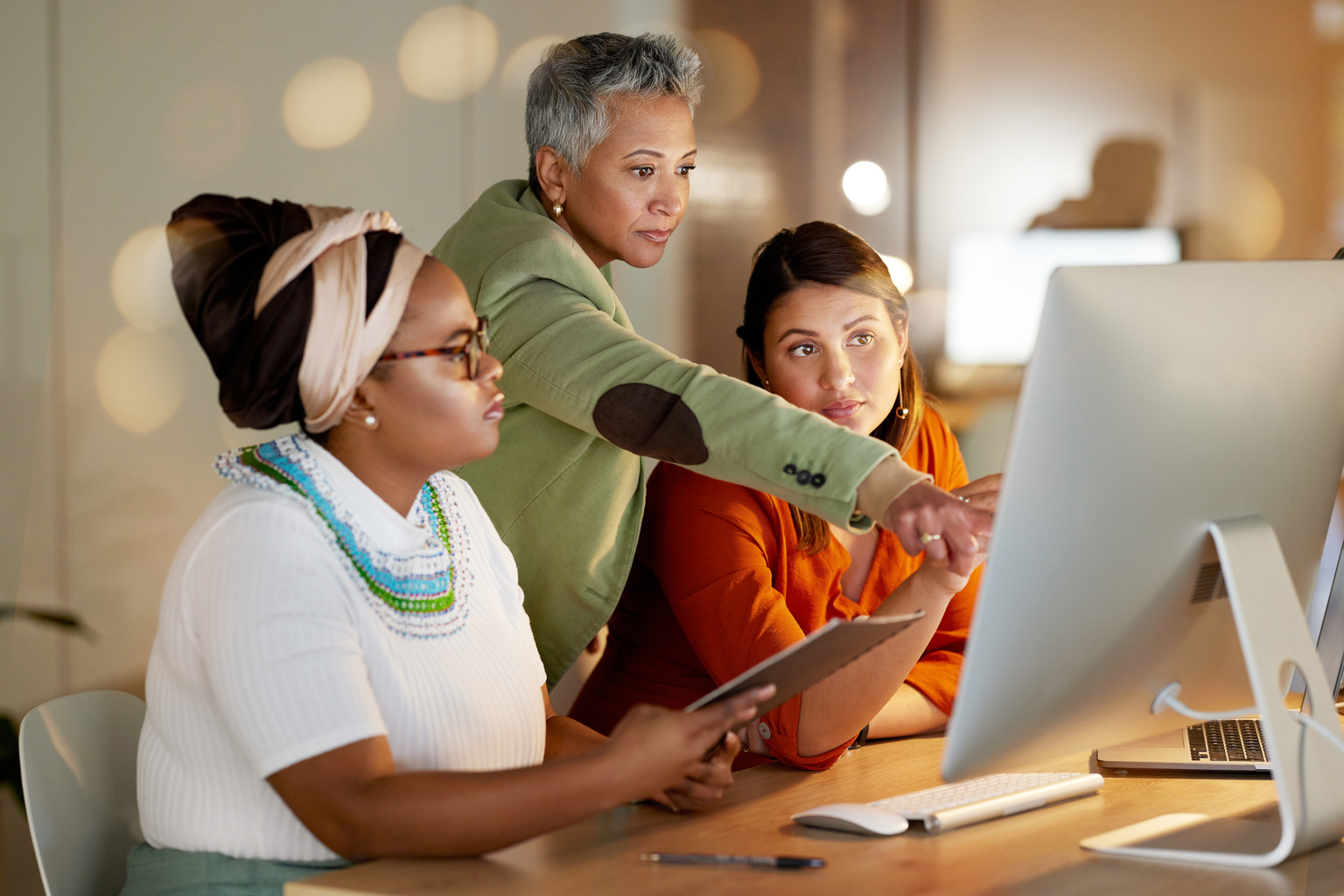 Three nursing professionals meeting to review information on a computer screen