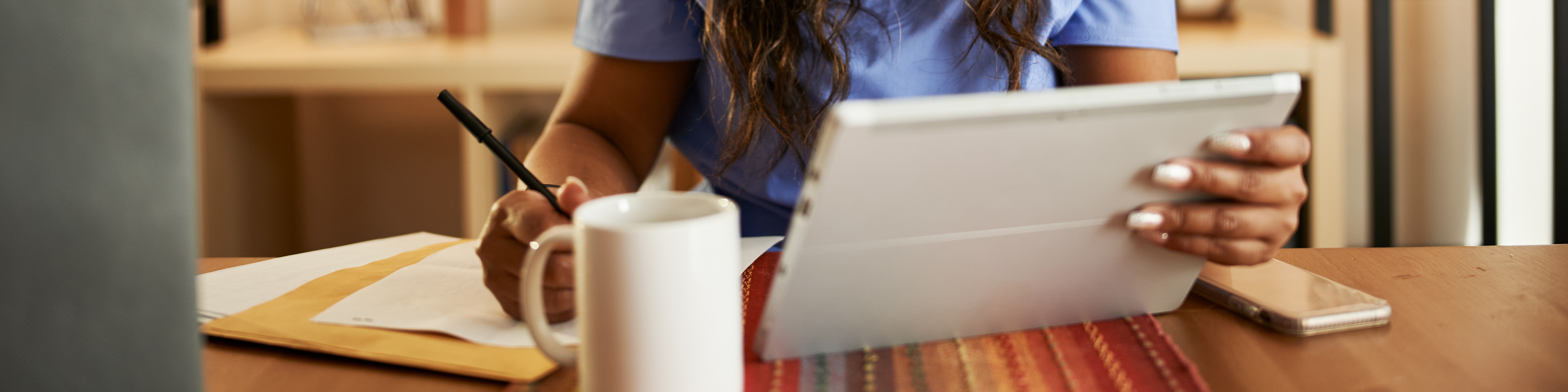 Nurse working from home doing paperwork and using tablet