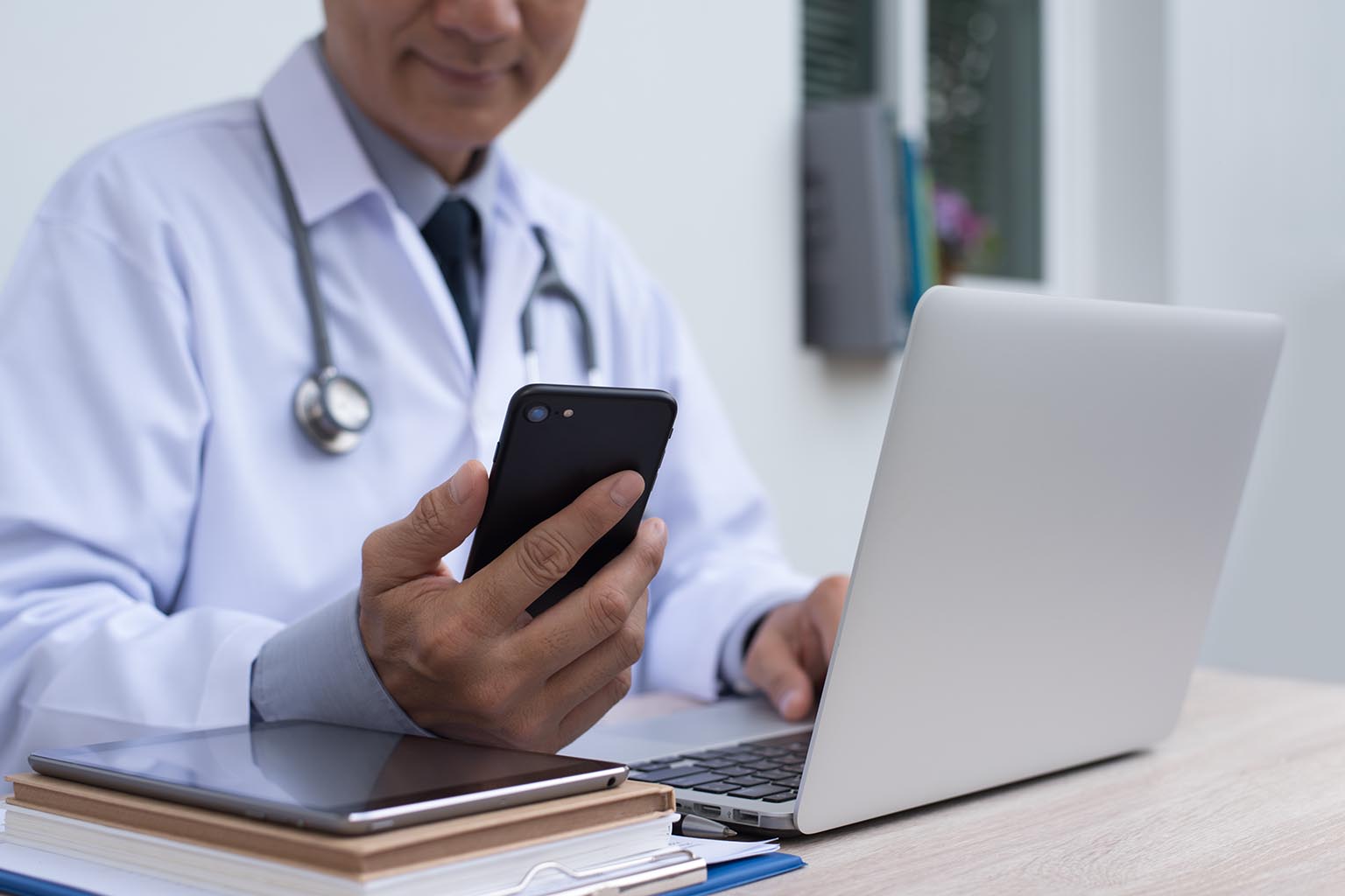 doctor on his computer looking at phone