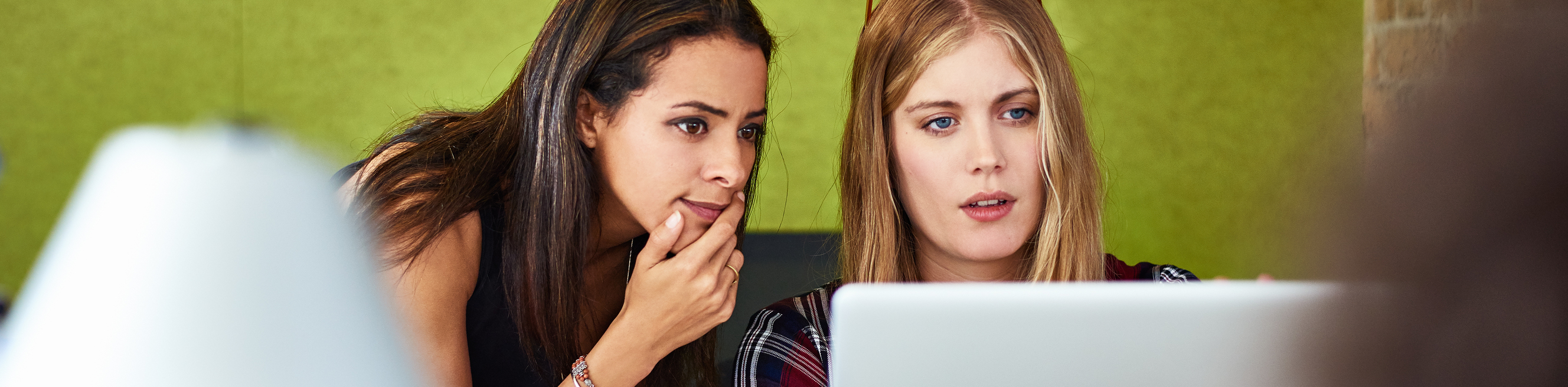 Female colleagues discussing over laptop in the office.