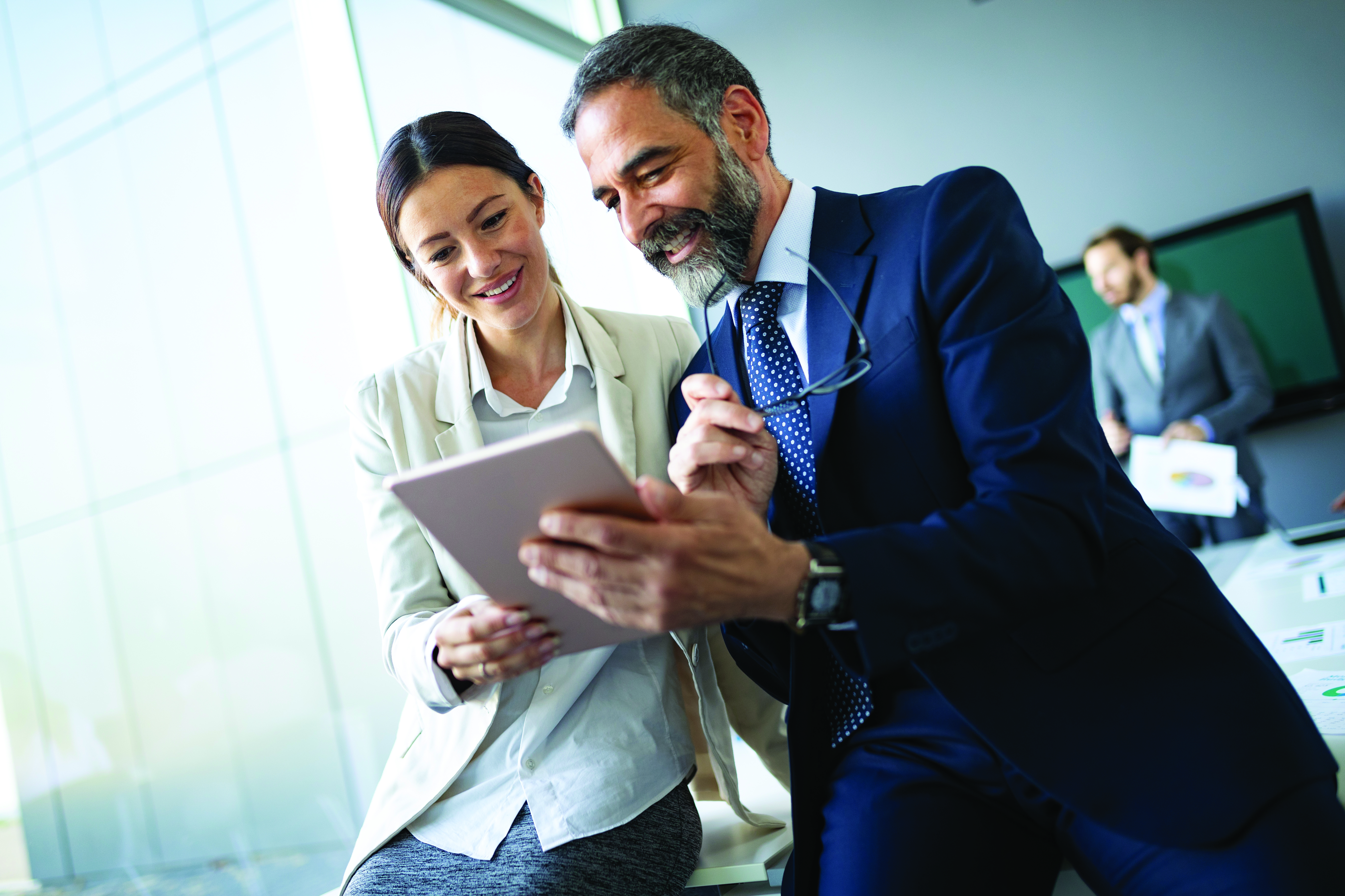 happy_business_colleagues_in_modern_office_using_tablet