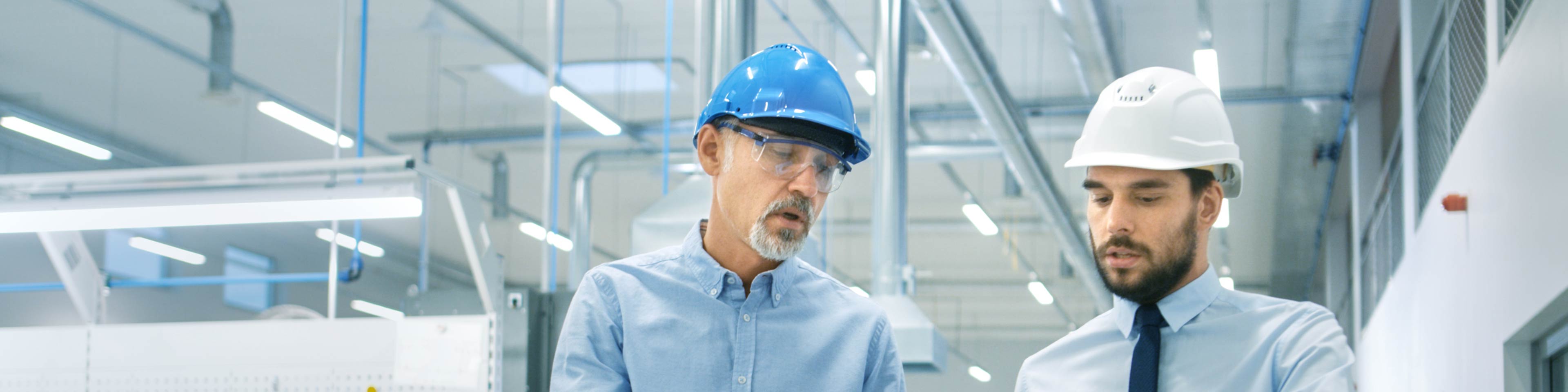 2 men wearing hard hats in a warehouse