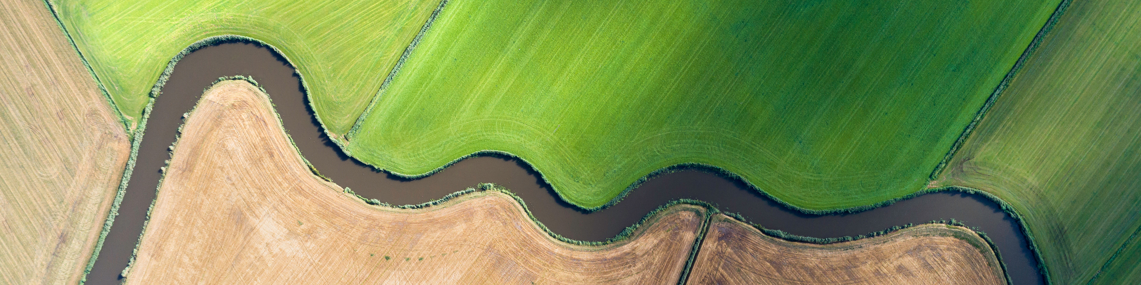 Aerial view of river bending through cultivated fields
