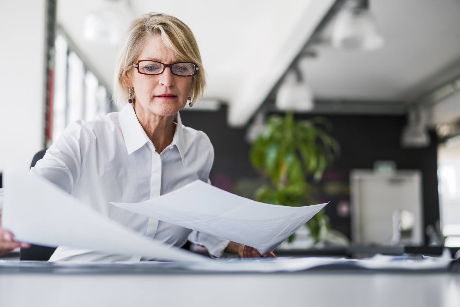 Businesswoman examining documents at desk 