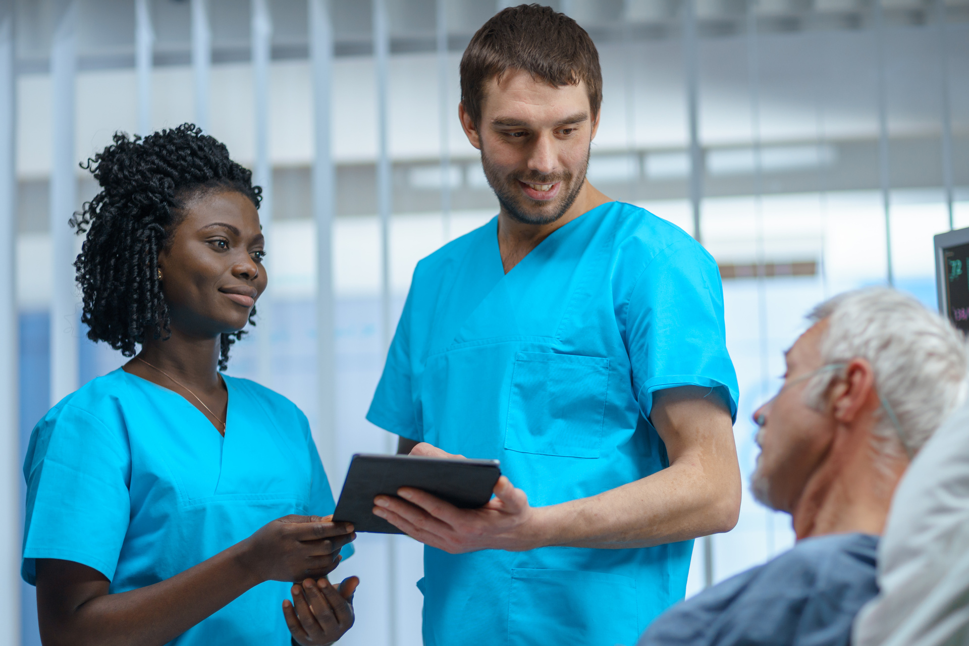 Hospital patient lying in bed with two healthcare professionals at bedside