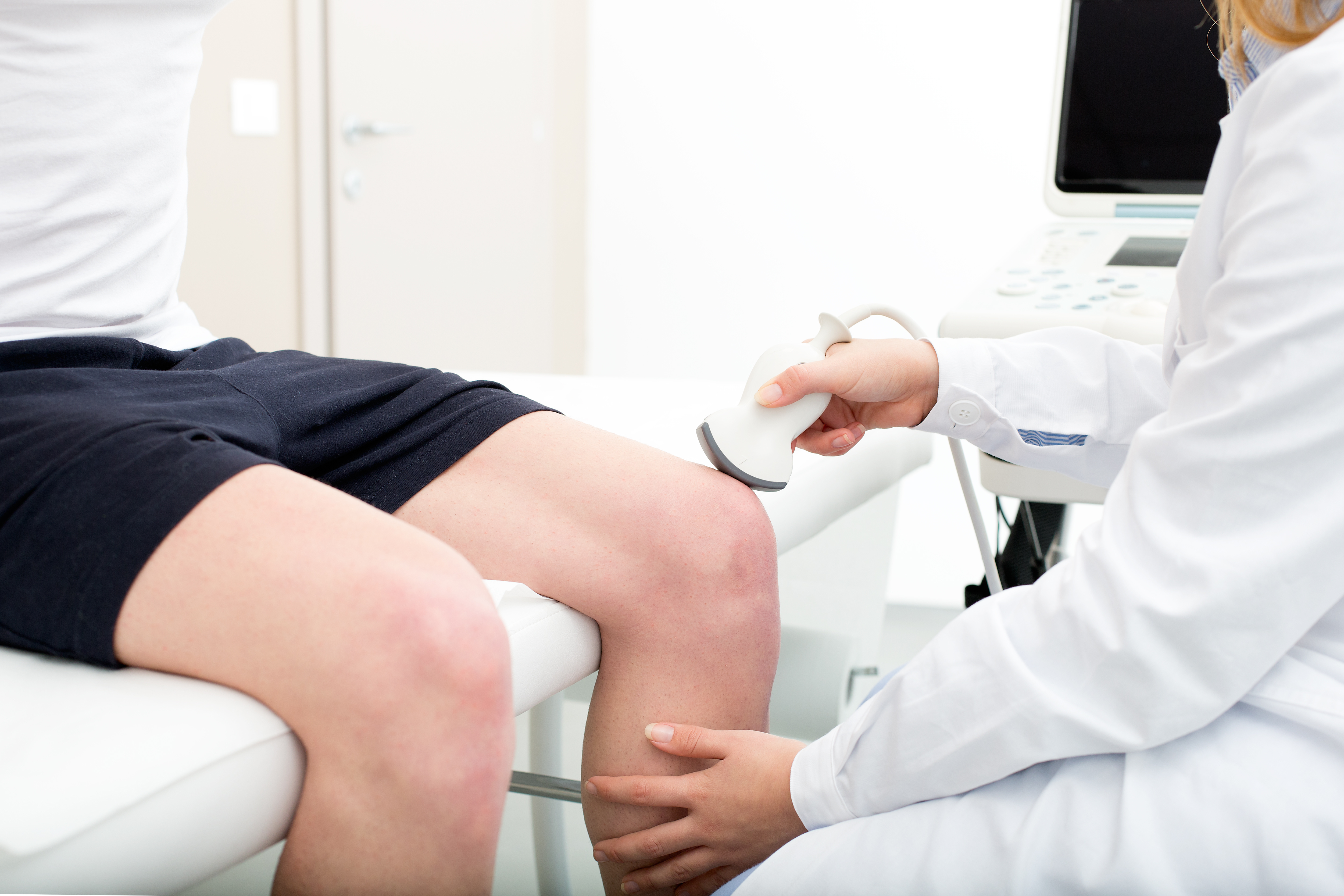 A doctor performing an ultrasound on a patient's knee