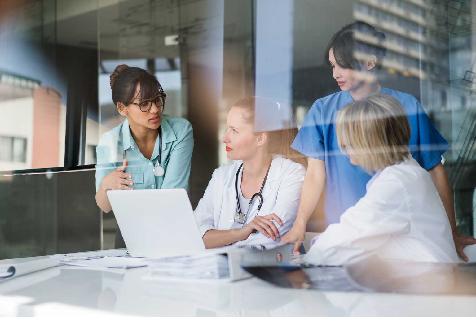 A photo of female doctors discussing at laptop desk