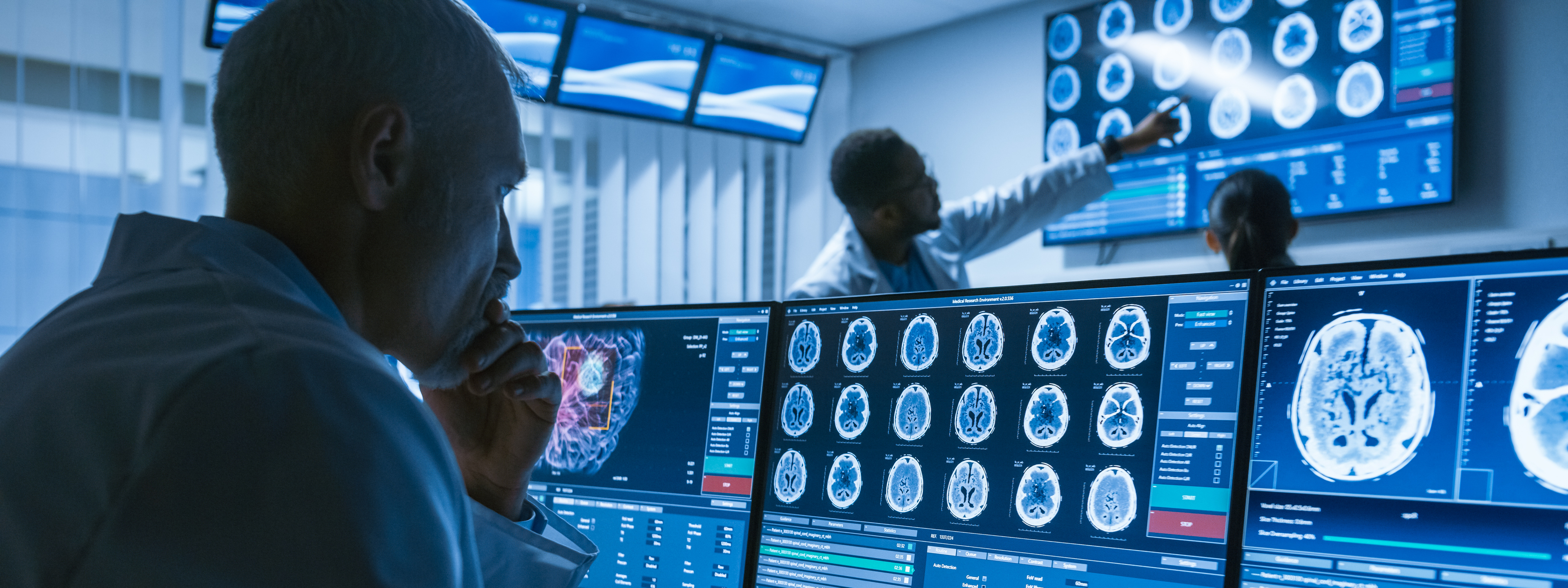 Over the Shoulder Shot of Senior Medical Scientist Working with CT Brain Scan Images on a Personal Computer in Laboratory