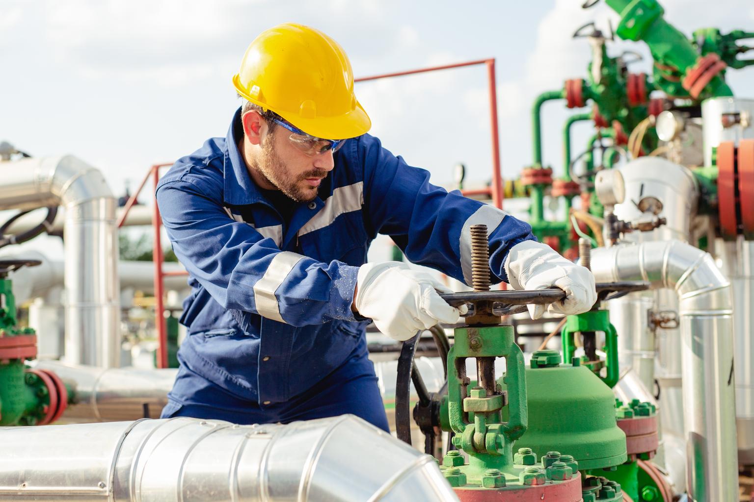 Oil worker is turning valve on the oil pipeline