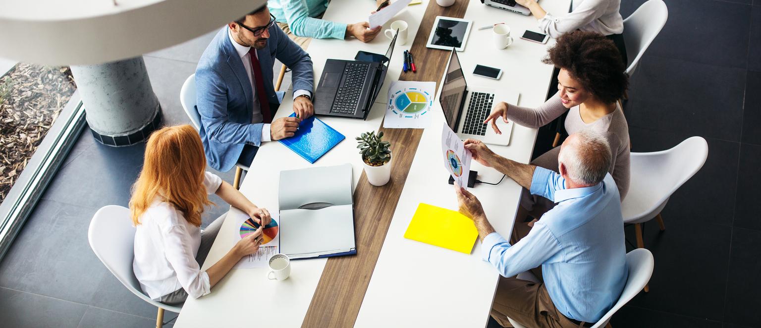 above photography shot of business meeting with employees sitting on a modern white and wood desk and white chairs, Q3 2021, TAA NA US - Preparer