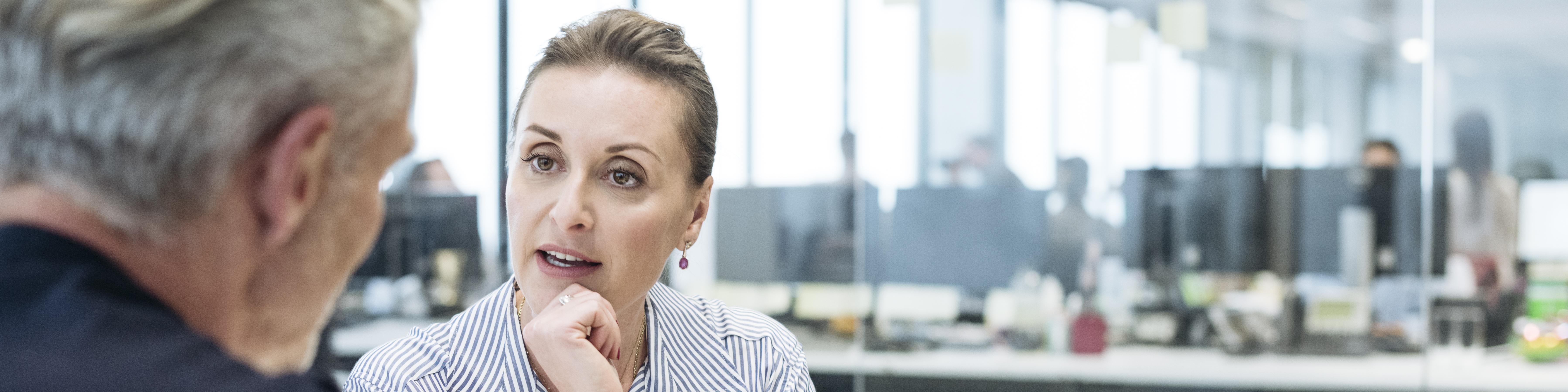 Businesswoman pointing to tablet and explaining to male colleague