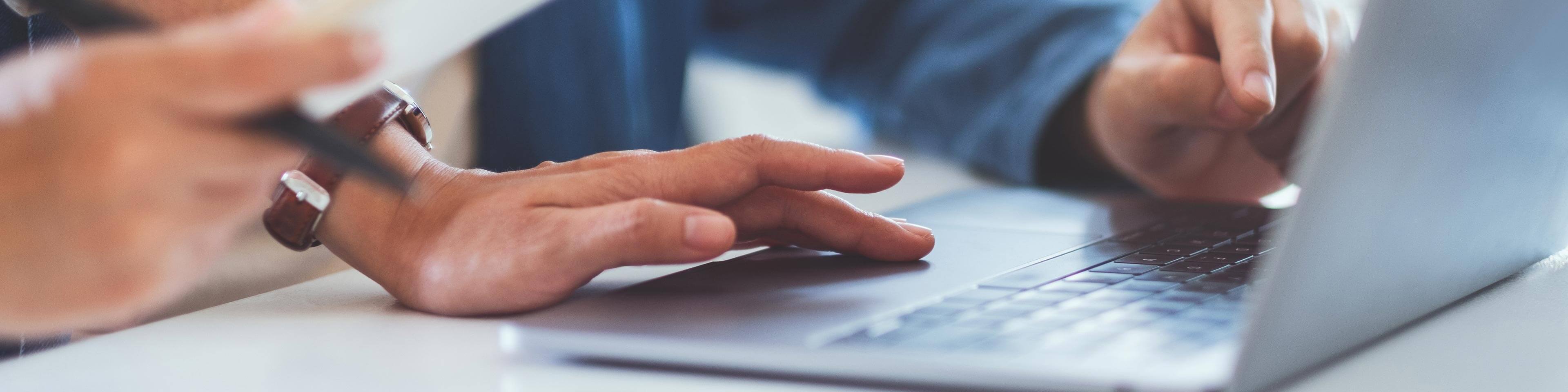 two people in business casual clothing pointing at a laptop