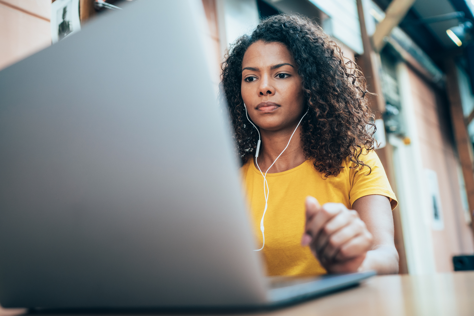 Women using earphones connected to laptop in an open area of house