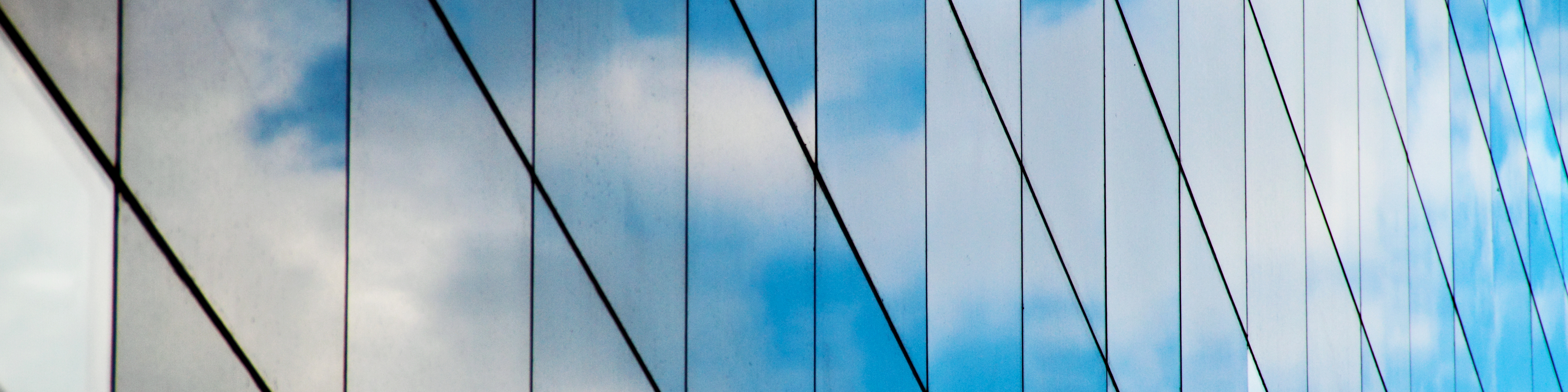 A reflection of clouds and sky in a mirrored glass building,