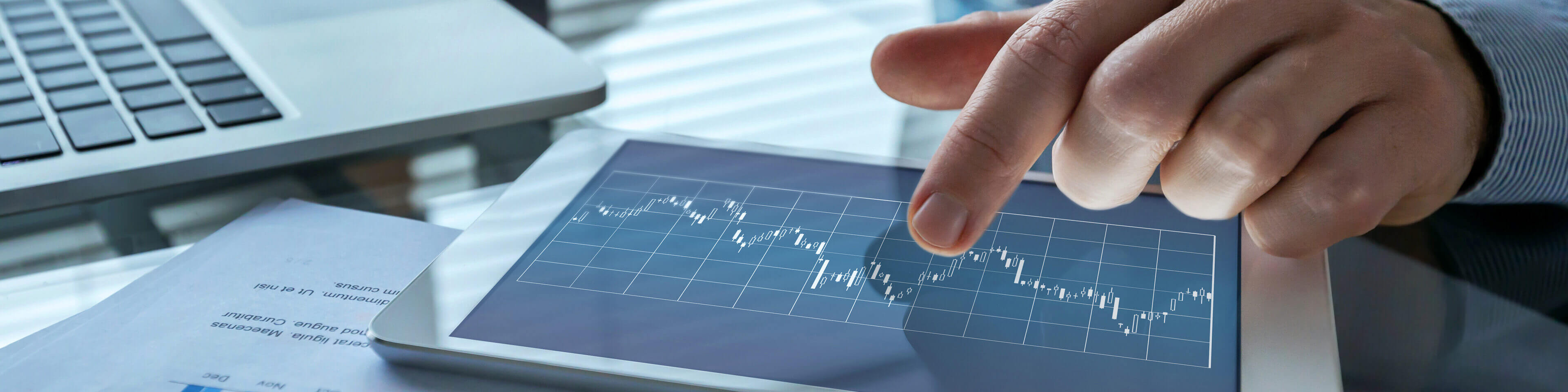 man's hand touching tablet with data charts on it.