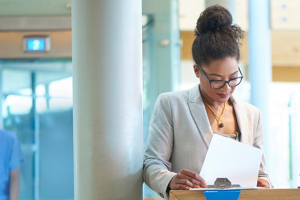 Nurse leader looking at clipboard at hospital lobby desk