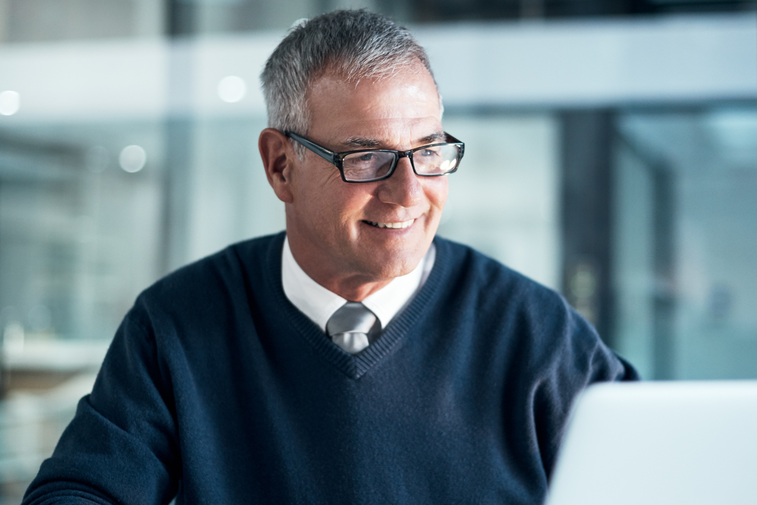 Shot of a mature businessman using a cellphone and laptop while working late in an office