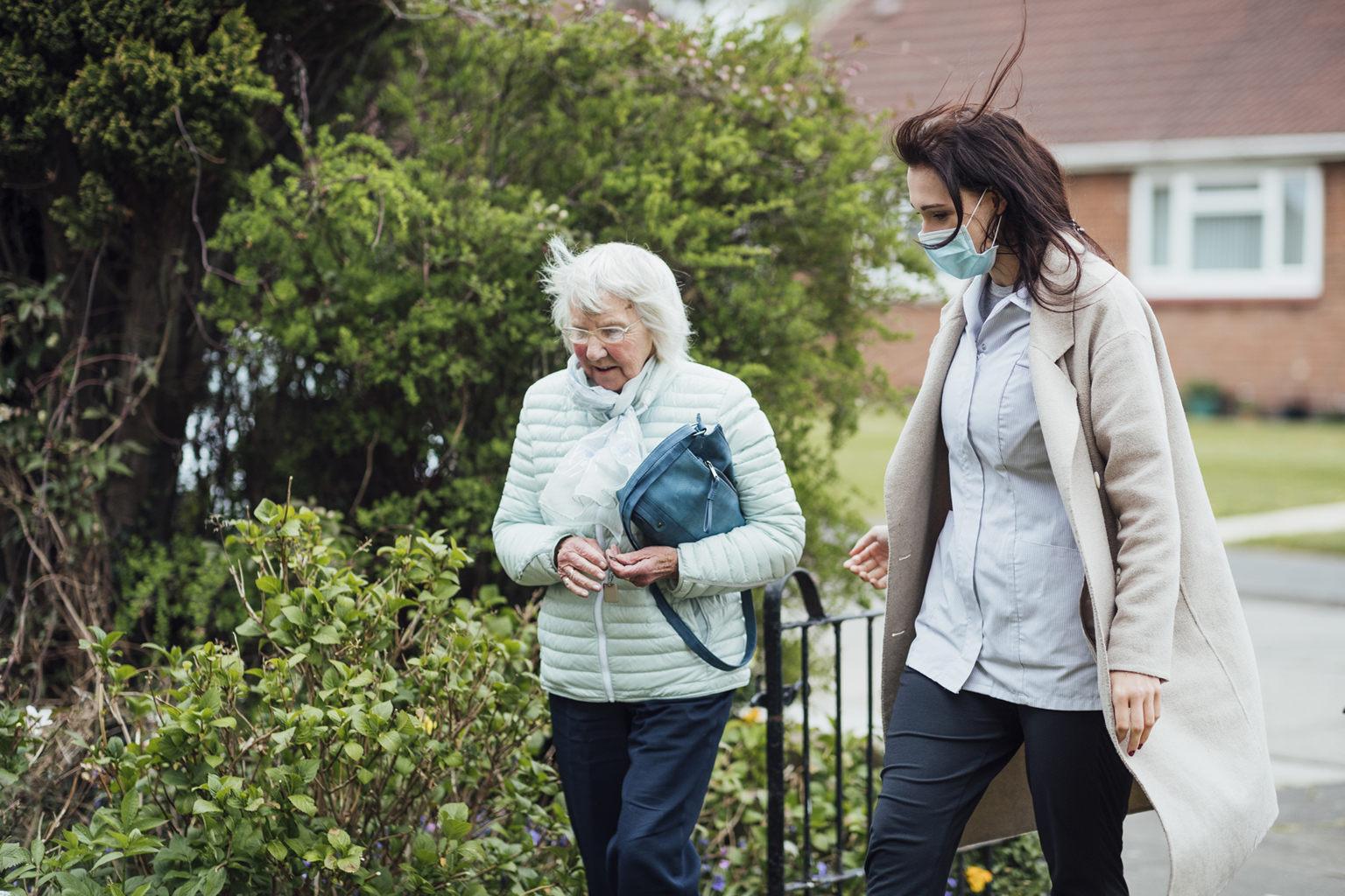 Middle-aged woman wearing a mask walking with older woman