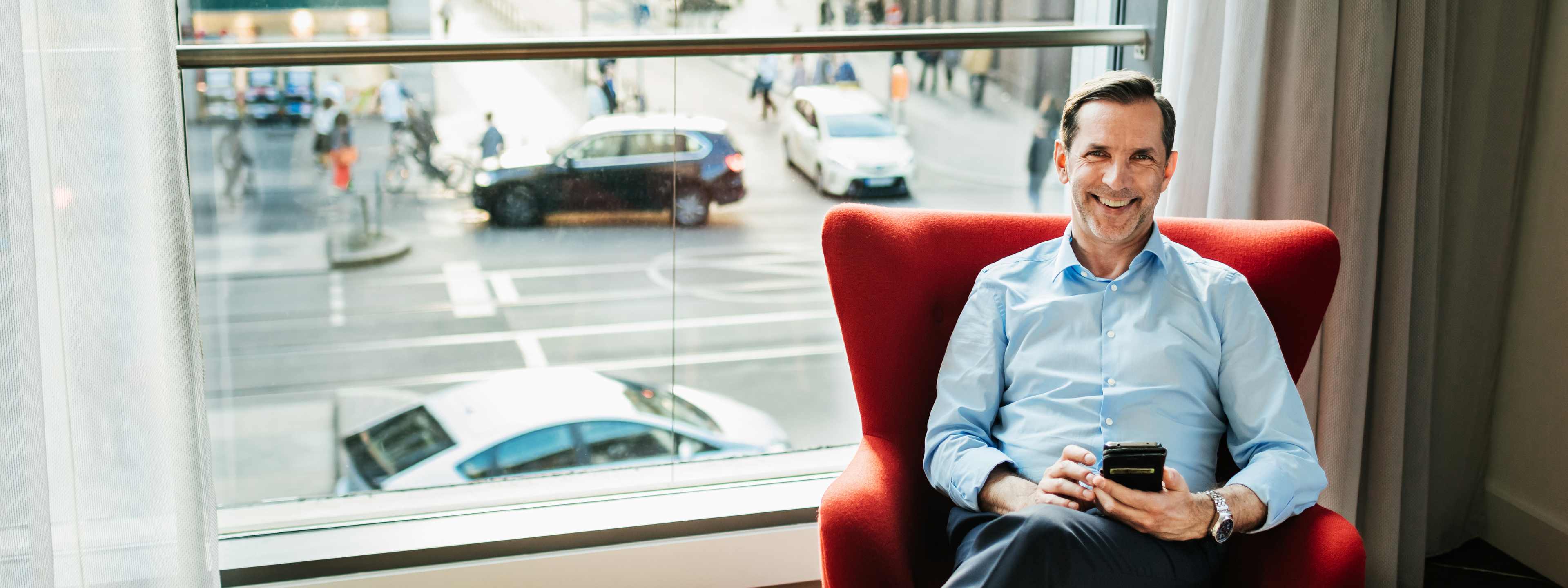 Happy businessman sitting in a chair in his hotel room and relaxing