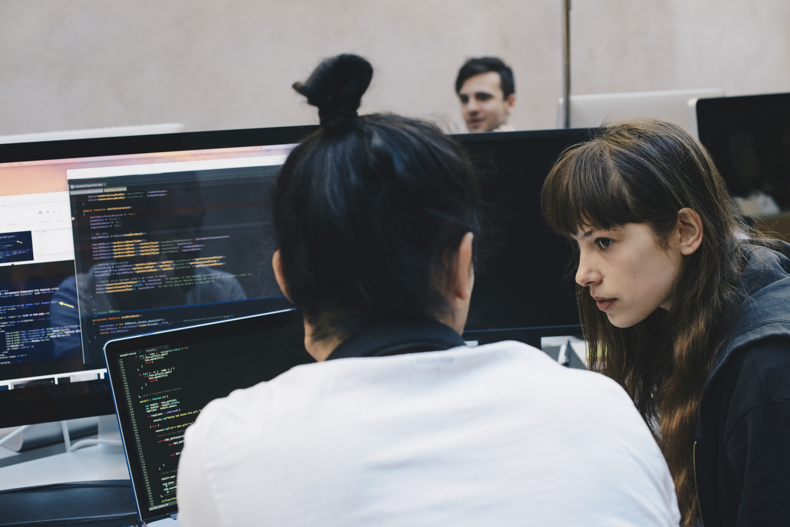 Male and female computer programmers discussing at office desk