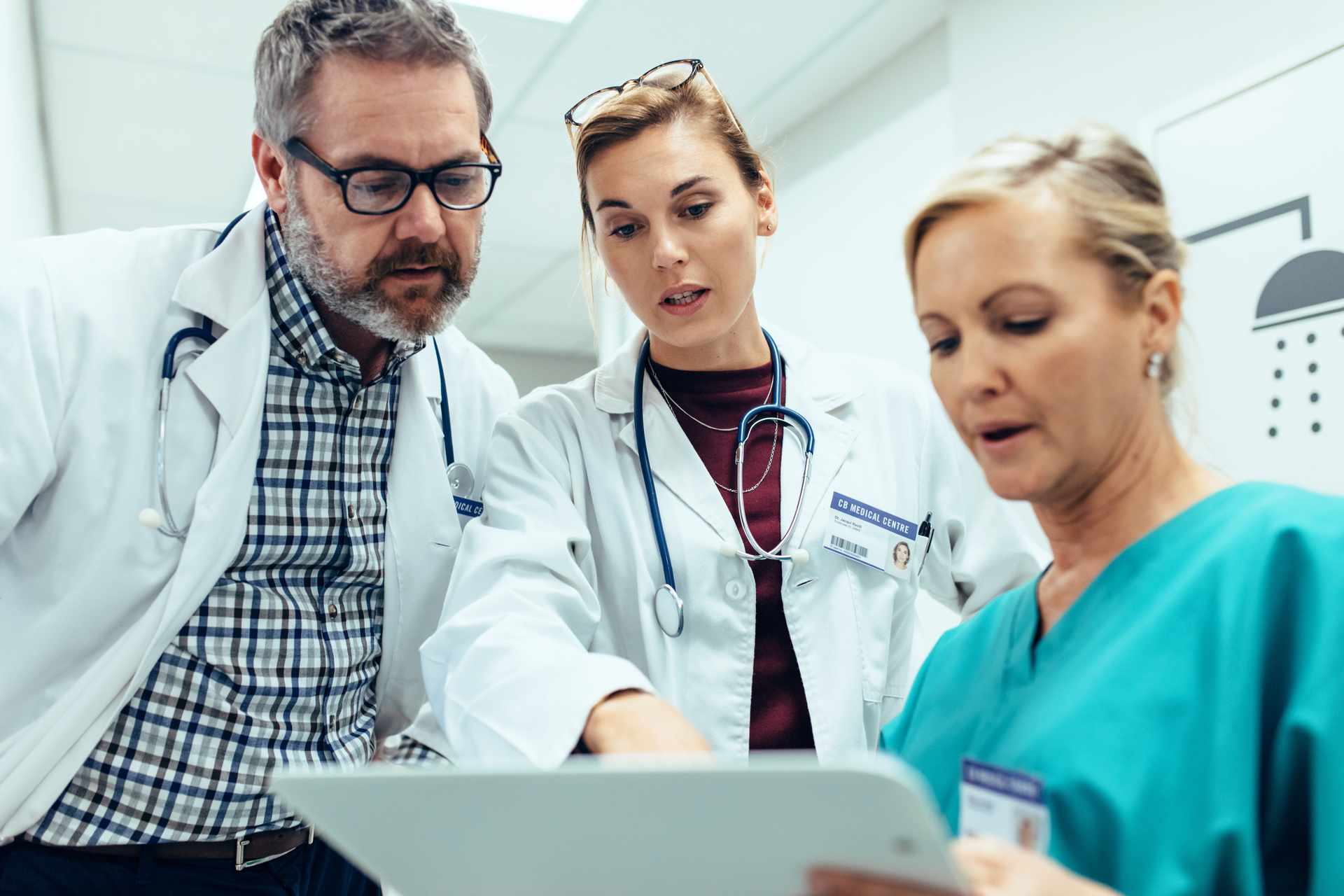 Three medical professionals reading patient information on tablet