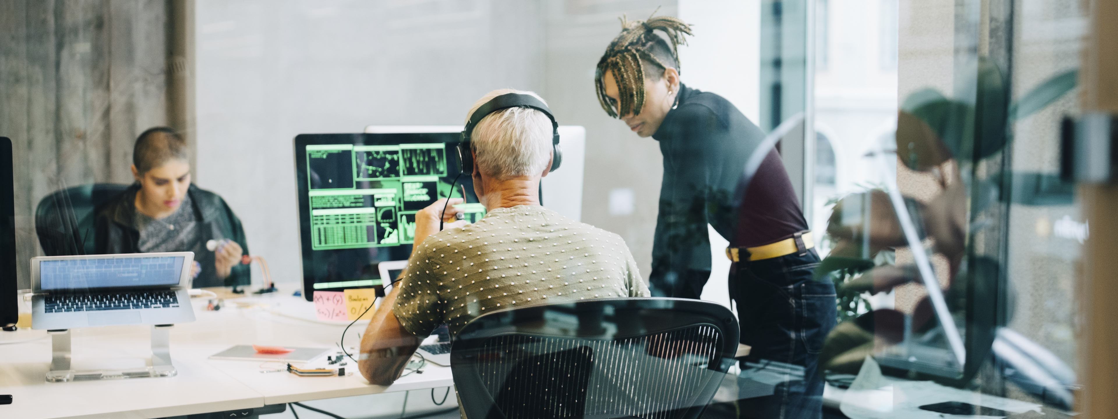 Male Engineer discussing with colleague while coding over computer at office