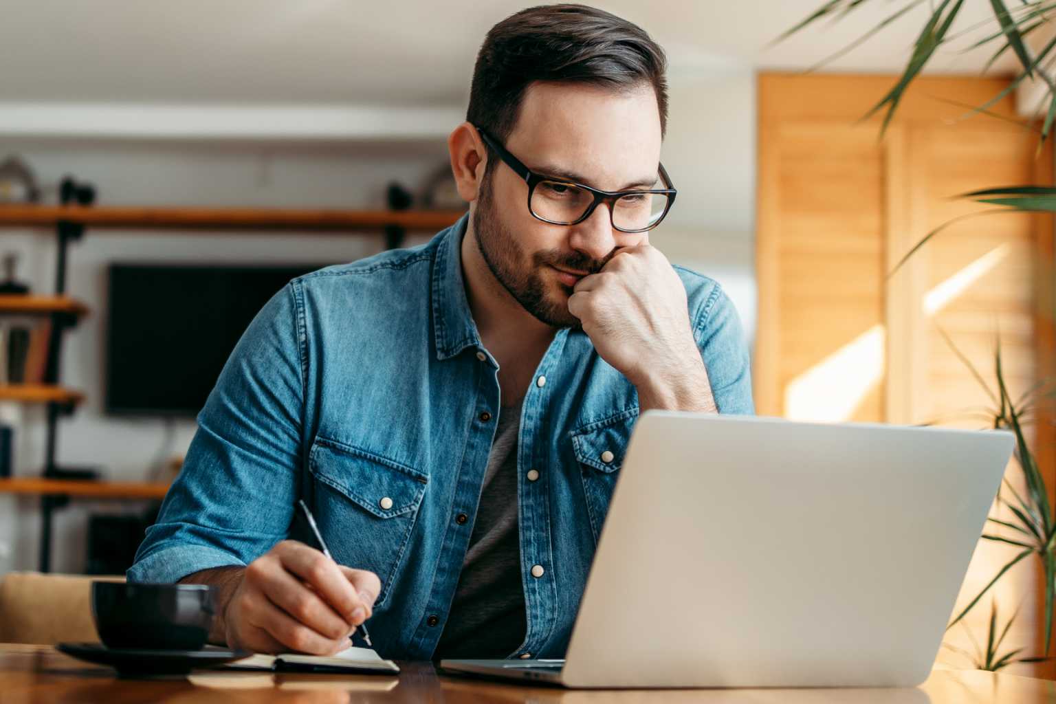 Man on laptop writing notes