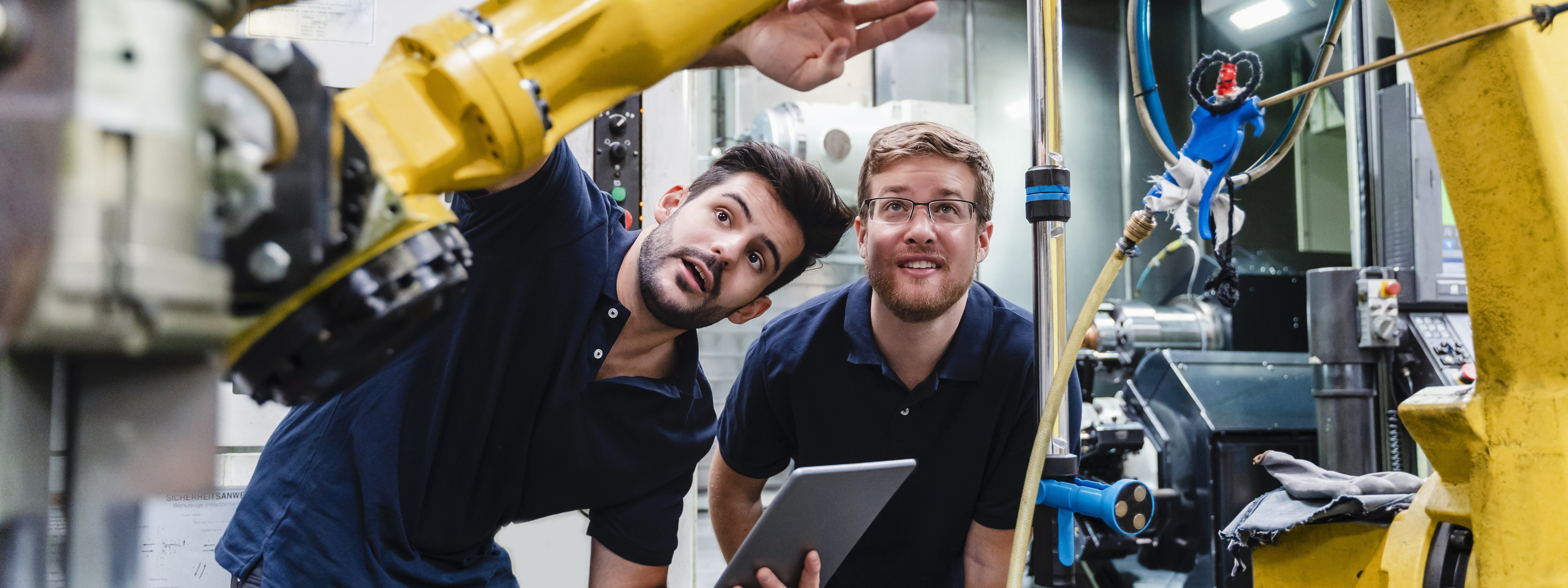 Colleagues examining machines at manufacture industry