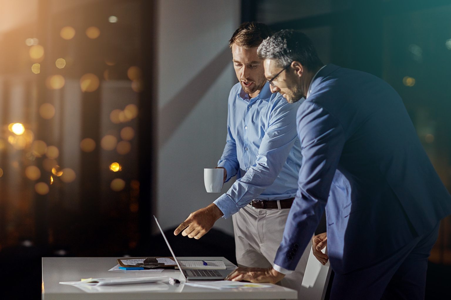 Shot of a coworkers using a laptop together while woking late at the office