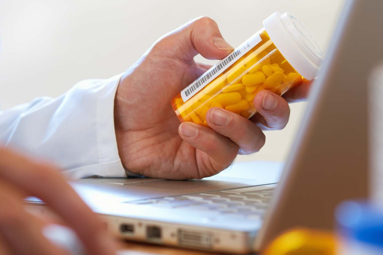 phamacist holding bottle of pills while using computer